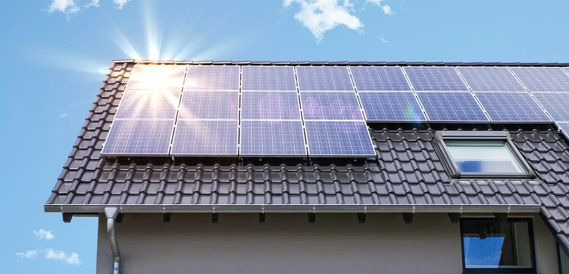 Photovoltaikanlage auf dem Dach eines Hauses mit blauen Dachpfannen, Sonne am Himmel